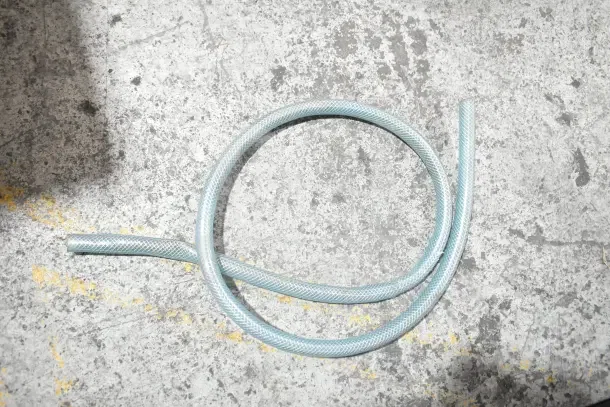 A coiled blue hose on a textured concrete surface.