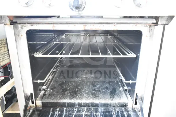 Southbend S241E commercial gas range with 4 burners, oven on casters. Interior shows signs of use and residue. Model S241E.
