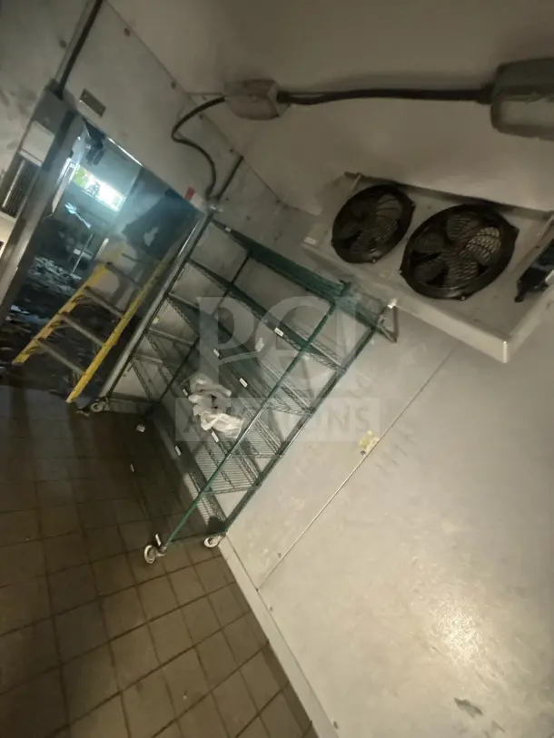 8'x12' walk-in box with evaporator fan, shown before removal. No contents or shelving included. Appears in functional condition.