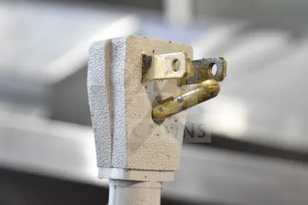 Close-up of a worn power plug with a textured surface, showing signs of use and discoloration.