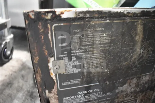 BK Industries commercial floor pressure fryer on casters, shows significant wear and usage. Label provides maintenance and safety info.