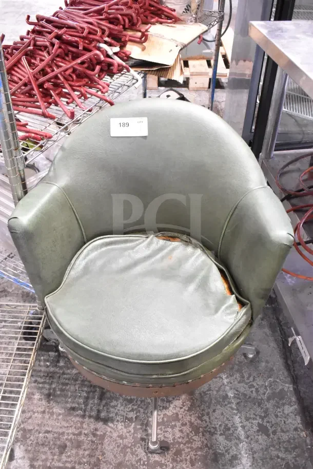 Green armchair with casters, worn seat cushion, and metal base. Tag marked "189." Used condition.