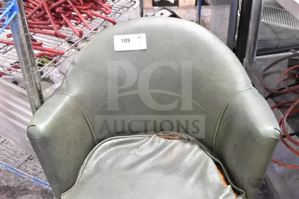 Green armchair on casters with worn seat upholstery, visible tear. Appears vintage, numbered auction tag 189 attached.
