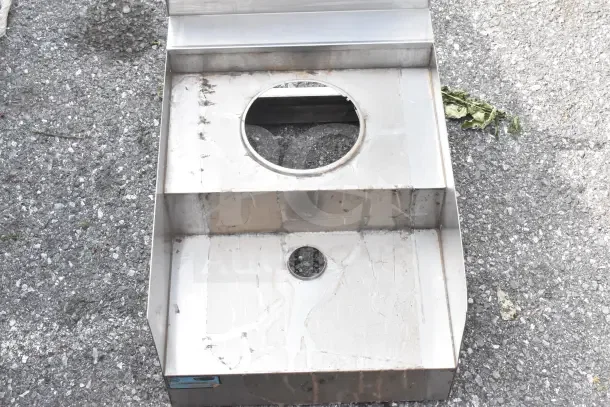 2-tier stainless steel counter with circular cutouts, no legs. Used condition, some surface wear visible.