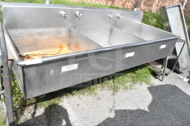 Commercial 3 bay sink, stainless steel, with faucets, mild rust and wear, dimensions approx. 6ft wide; ideal for kitchens.