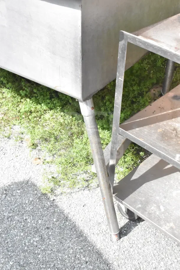 Commercial 3 bay sink, stainless steel, used condition. Visible scratches on the surface with sturdy legs and frame.