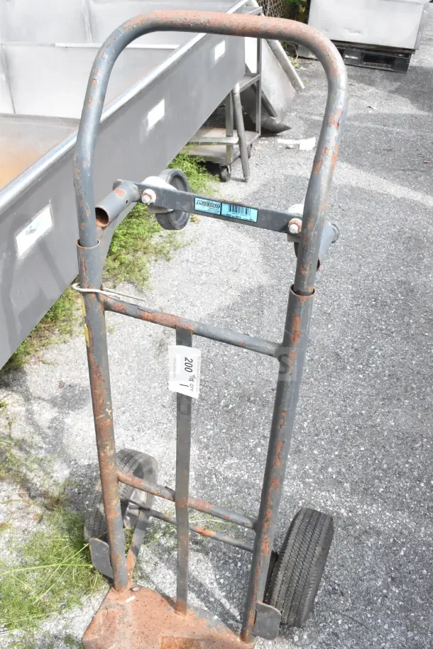 Rusty metal furniture dolly with two wheels, worn condition. Label indicates "200 lb load capacity."