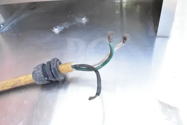 Frayed electrical cord for a Jackson Conserver XL dishwasher, indicating need for repair. Stainless steel surface visible.