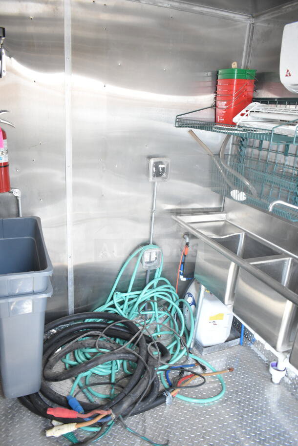 2021 Rock Solid Cargo 8.5'x24' food trailer interior with stainless steel sinks, hoses, electrical outlets, and equipment.