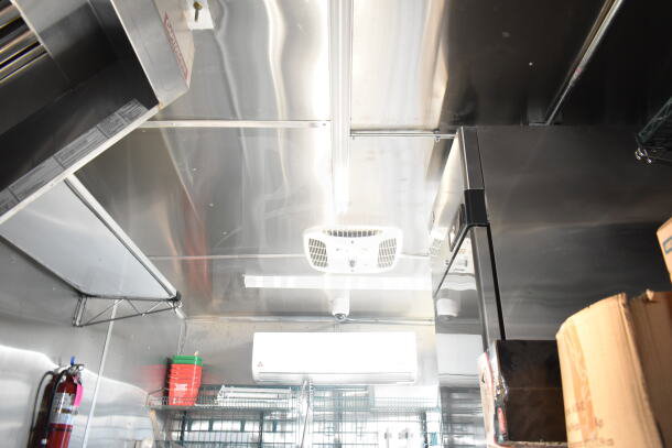 Interior view of 2021 Rock Solid Cargo 8.5'x24' food trailer. Stainless steel walls, ceiling, A/C unit, and shelving visible.