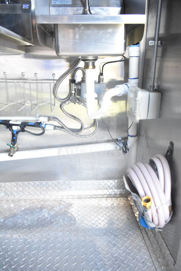 Interior of 2021 Rock Solid Cargo food trailer showing plumbing details and diamond plate flooring.
