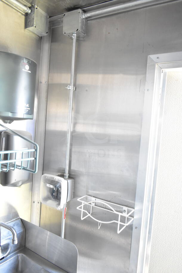 Interior of 2021 Rock Solid Cargo 8.5'x24' food trailer with stainless steel walls, hand sanitizer dispenser, and outlet.