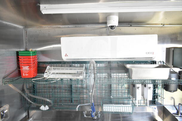 Interior view of a 2021 Rock Solid Cargo 8.5'x24' food trailer featuring green wire shelving, sink with sprayer, red cleaning buckets, and VentusX unit.