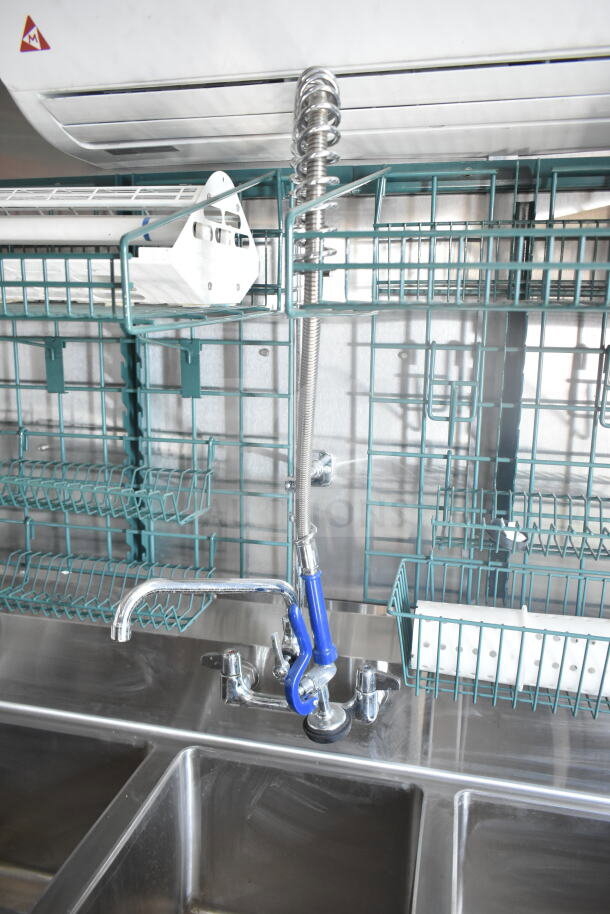 Interior view of a 2021 Rock Solid Cargo 8.5'x24' food trailer featuring a stainless steel sink and commercial faucet, with storage racks above.