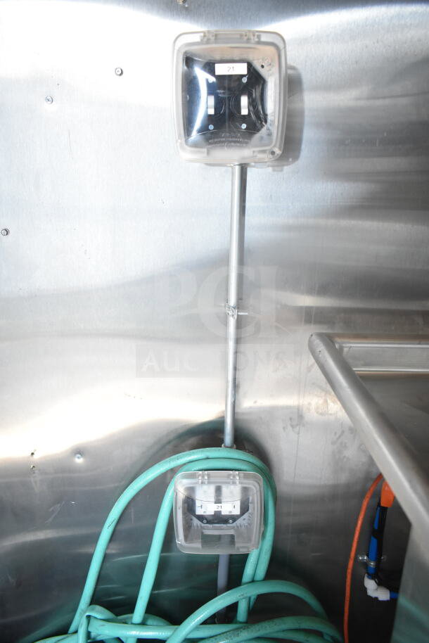 Electrical outlets with clear covers in a 2021 Rock Solid Cargo 8.5'x24' food trailer, braided green hose underneath.