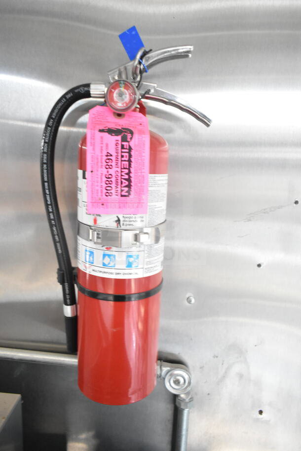 Fire extinguisher with Fireman Equipment tag mounted in a food trailer.