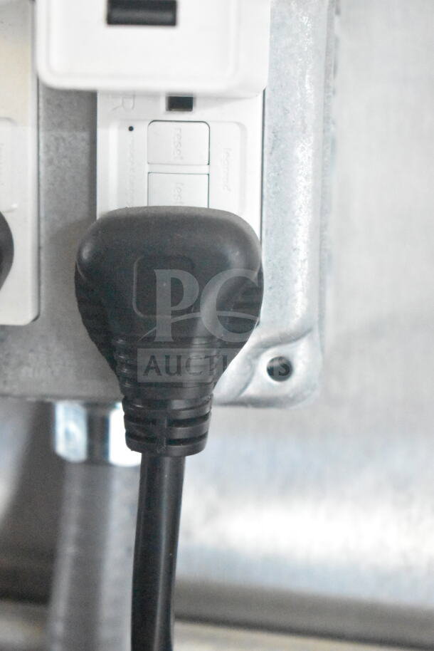Close-up of a black electrical plug inserted into a white power outlet inside a 2021 Rock Solid Cargo food trailer.