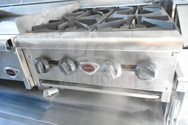 Industrial gas cooktop with four burners by Wells, features control knobs and robust metal construction, ideal for food service.