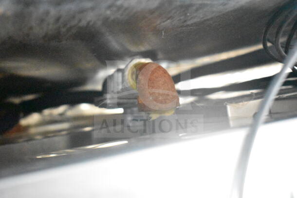 Close-up of a rusted metal pipe under the 2021 Rock Solid Cargo 8.5'x24' food trailer.