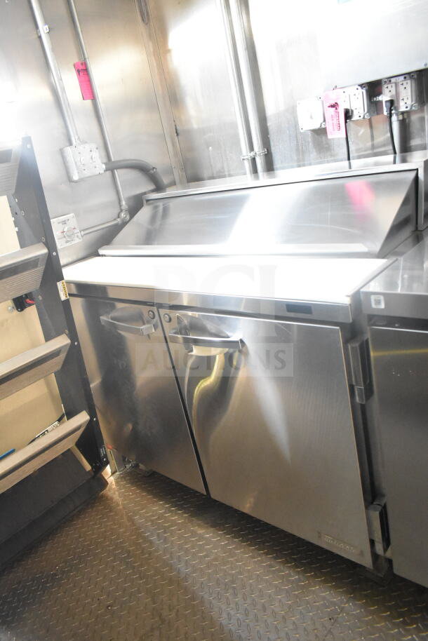 2021 Rock Solid Cargo 8.5'x24' food trailer interior. Stainless refrigeration suite with CaptiveAire grease hood visible.