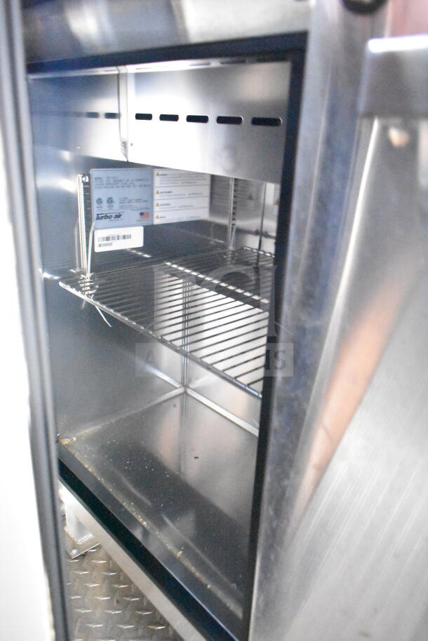 Interior view of the 2021 Rock Solid Cargo food trailer, showcasing a Turbo Air refrigerator with clean stainless steel racks.
