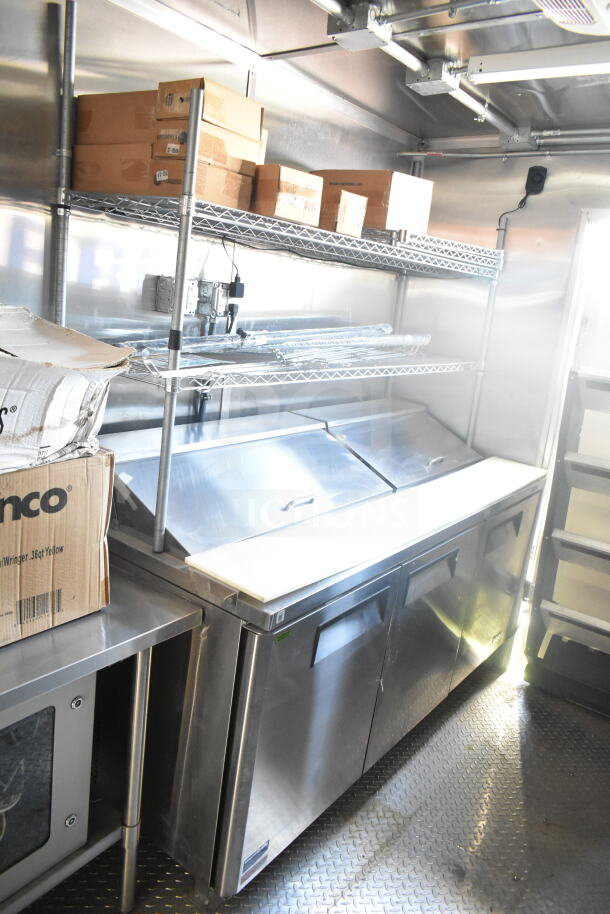 2021 Rock Solid Cargo 8.5'x24' food trailer interior with stainless steel refrigeration suite, shelving, and storage boxes.
