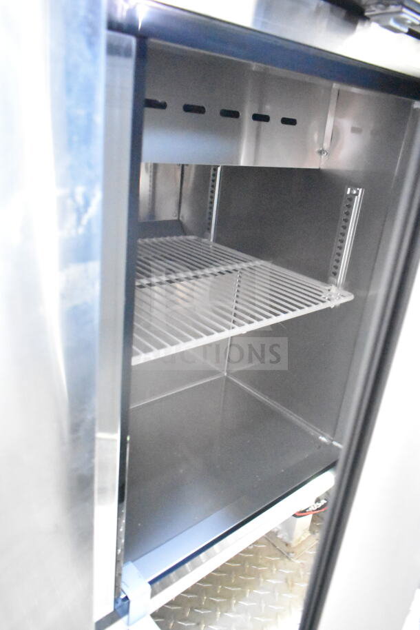 Interior view of a Rock Solid Cargo food trailer refrigeration unit with metal shelving, part of a full kitchen setup.