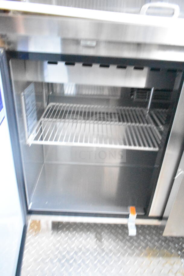 Interior of a 2021 Rock Solid Cargo food trailer featuring a stainless steel refrigeration unit with wire shelving.