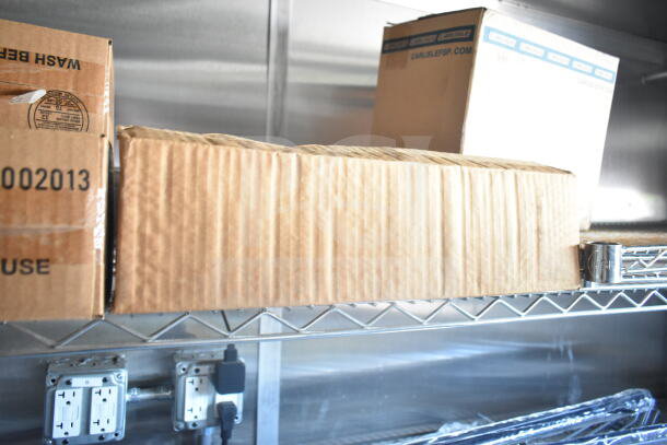 2021 Rock Solid Cargo 8.5'x24' food trailer interior showing shelving with cardboard boxes. Equipped with outlets.