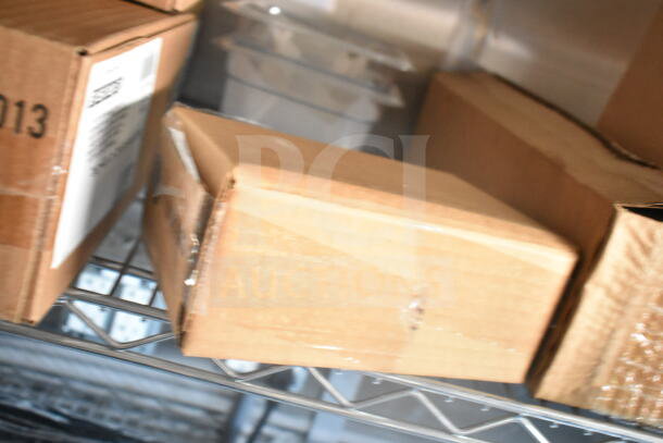 Cardboard boxes on metal shelving inside a 2021 Rock Solid Cargo food trailer. The trailer features a CaptiveAire grease hood and fire suppression system.
