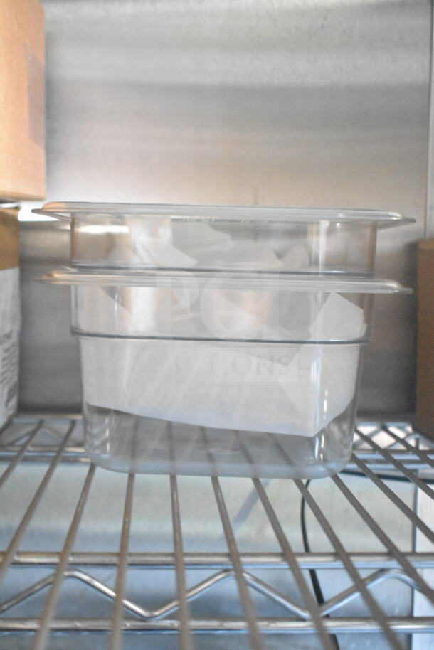 Clear food storage containers on a metal shelf inside a refrigerated unit. No visible labels or markings.