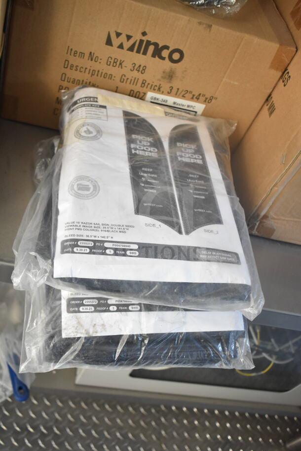 Plastic-wrapped printed documents on metal shelf; Winco box with item details in background.