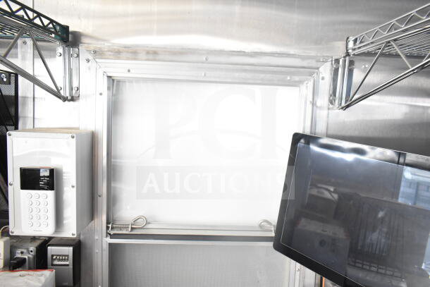 Interior view of a 2021 Rock Solid Cargo food trailer with electronic control panel, shelving, and part of a monitor.