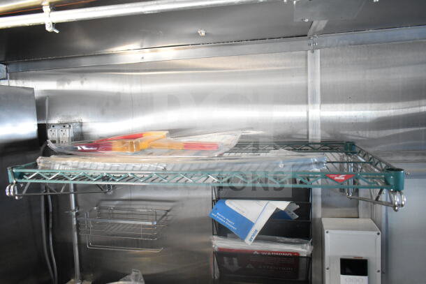 Interior view of the 2021 Rock Solid Cargo food trailer showing stainless steel shelving, electrical outlets, and storage bins.