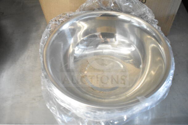 Stainless steel mixing bowl with plastic wrap, placed on a metal surface, showing minor residue inside.