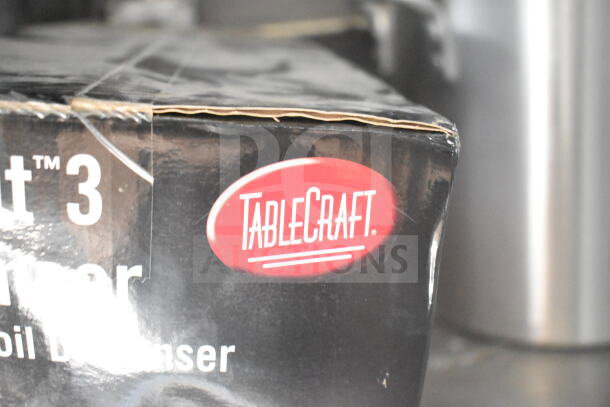 Close-up of a TableCraft logo on a black box. The label is oval-shaped with white text on a red background.