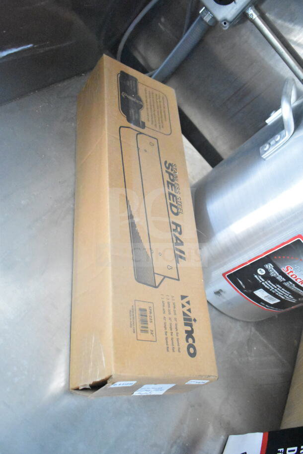 Box of Winco stainless steel speed rail, model SPR-22, on a metal surface, with a stock pot nearby.