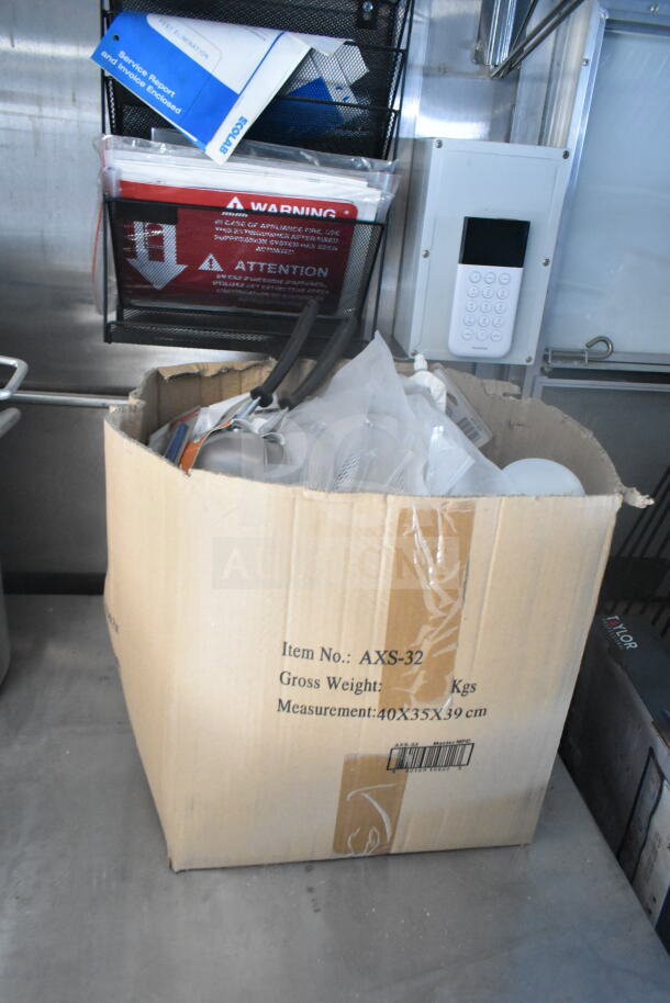 Cardboard box with kitchen supplies in a 2021 Rock Solid Cargo food trailer. Wall-mounted folders and control panel visible.