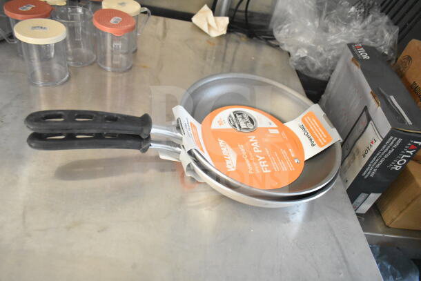 Two Volrath PowerCoat2 fry pans with handles and labels on a stainless steel surface, alongside containers and packaging.
