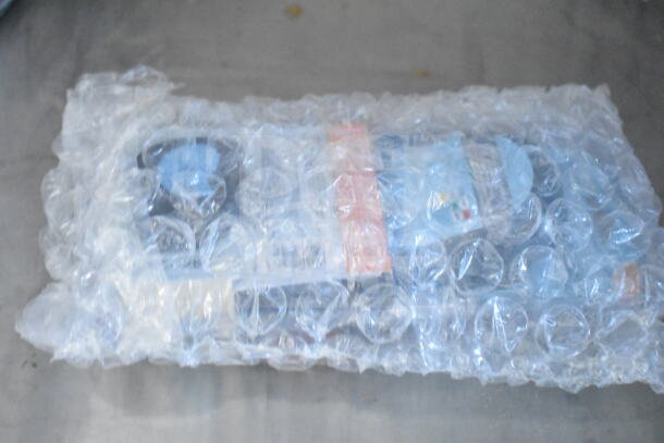 Bubble-wrapped package containing contents not visible, resting on a surface.