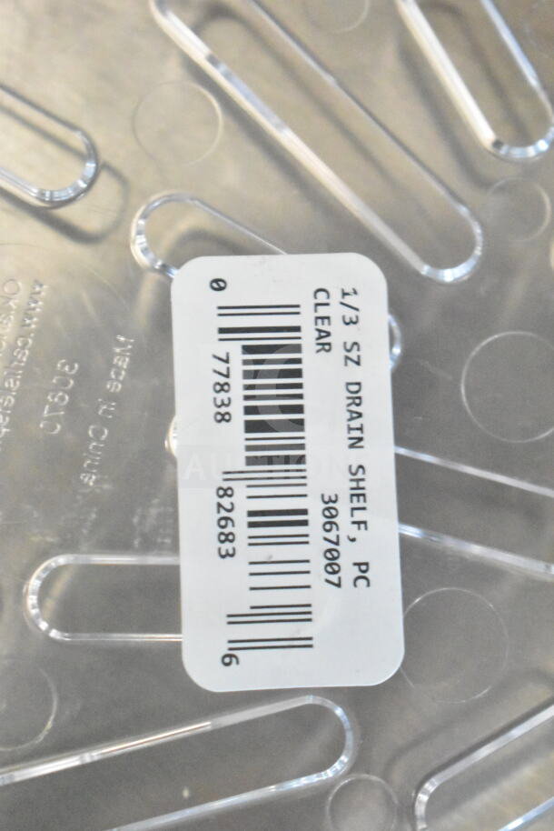 Barcode label for a 1/3 size clear drain shelf with part number 3067007 visible on a transparent surface.
