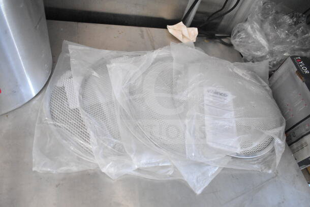 Plastic-wrapped round mesh screens on a stainless steel table, next to a cylindrical container and a box labelled "Taylor."