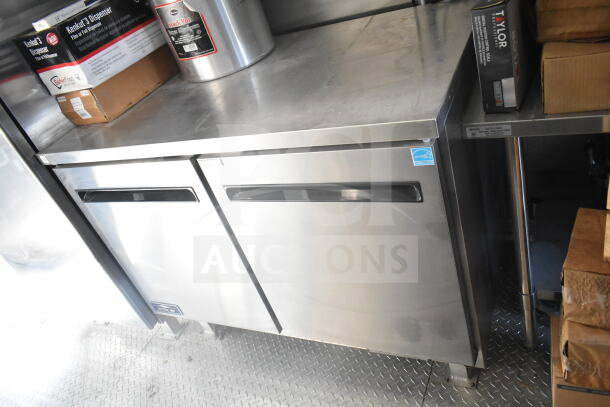 2021 Rock Solid Cargo 8.5'x24' food trailer interior showing refrigeration suite with stainless steel finish and storage boxes.