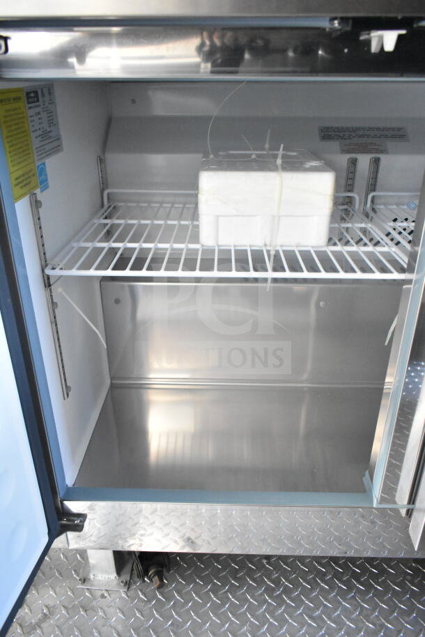 Interior view of 2021 Rock Solid Cargo food trailer refrigeration suite with metal shelving and secure packing block.