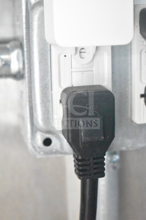 Close-up of black power plug connected to a white outlet in a 2021 Rock Solid Cargo 8.5'x24' food trailer.