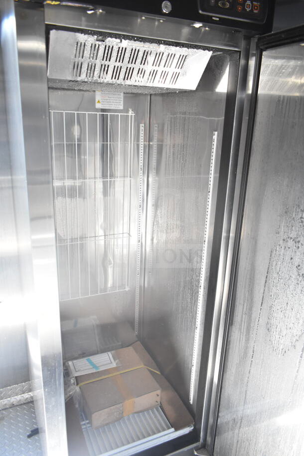Interior view of refrigeration unit in 2021 Rock Solid Cargo food trailer, features stainless steel walls and adjustable shelving.