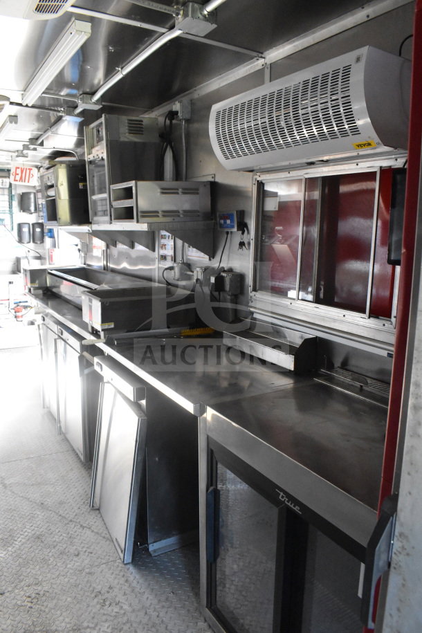 2021 Rock Solid Cargo 8.5'x28' food trailer interior. Stainless steel counters, refrigeration unit, and overhead storage.