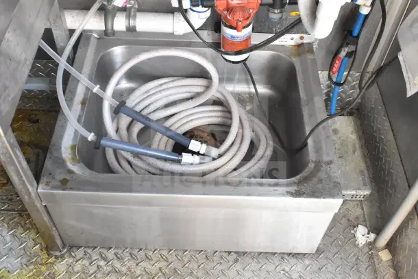 Stainless steel sink with coiled hoses, part of the 2021 Rock Solid Cargo food trailer.