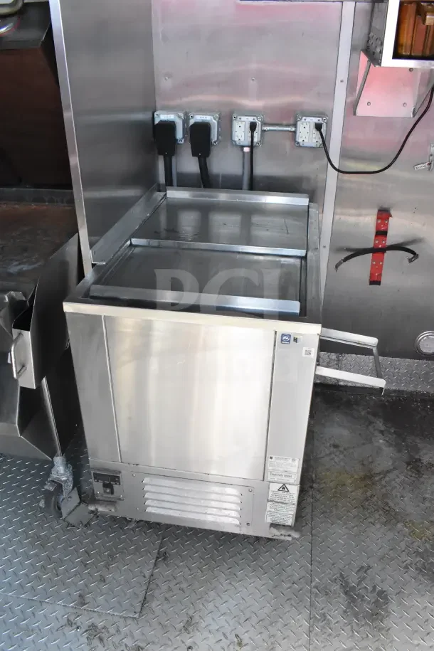 2021 Rock Solid Cargo 8.5'x28' food trailer interior with stainless steel refrigeration unit, mounted outlets, and non-slip flooring.