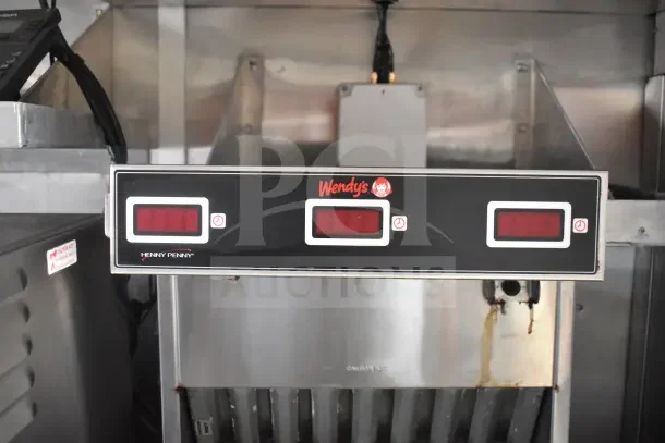 Interior of Rock Solid Cargo food trailer featuring a Henny Penny control panel with Wendy’s branding, mounted on stainless steel equipment.